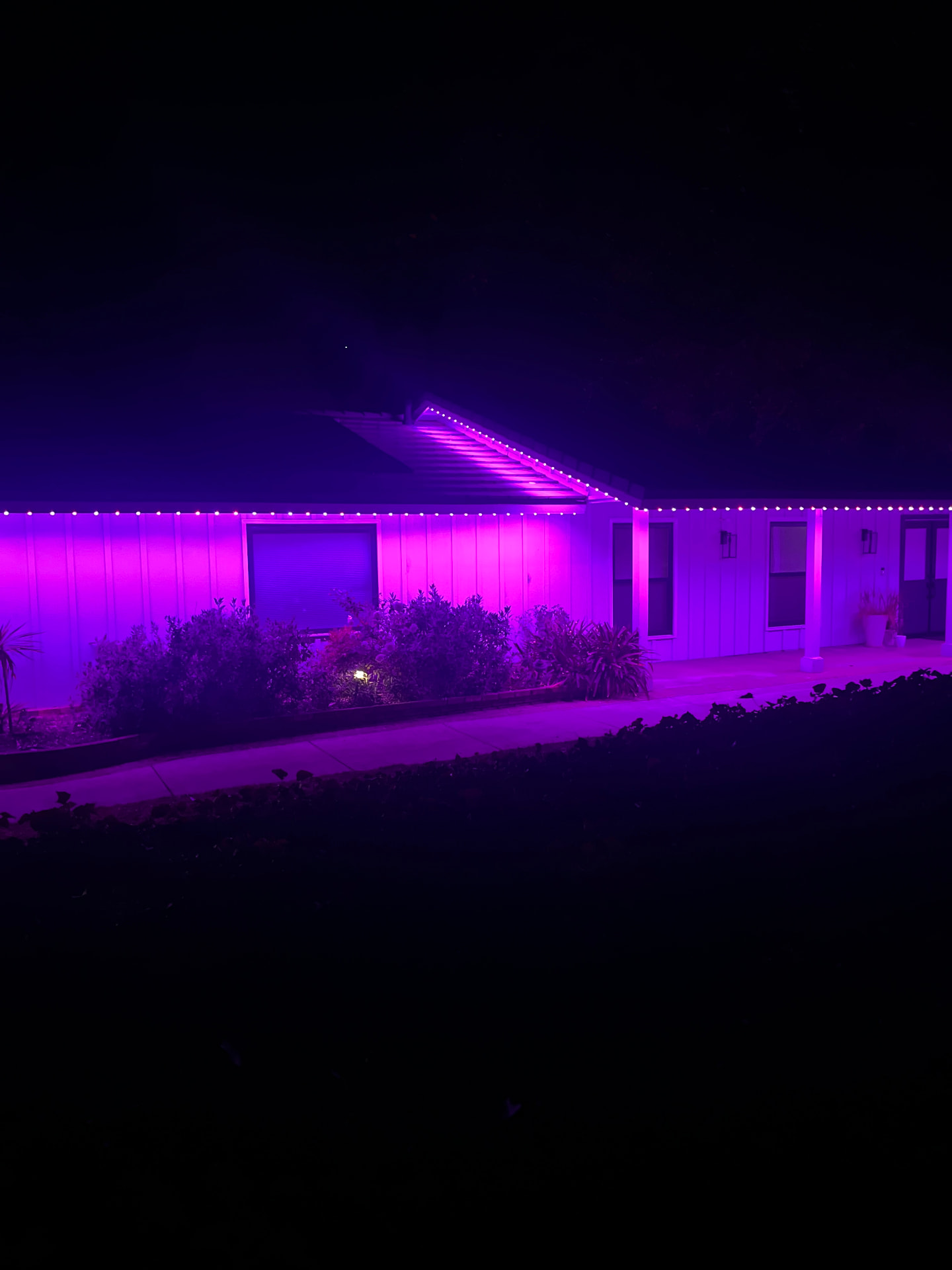 Purple permanent lighting across a single-story roofline