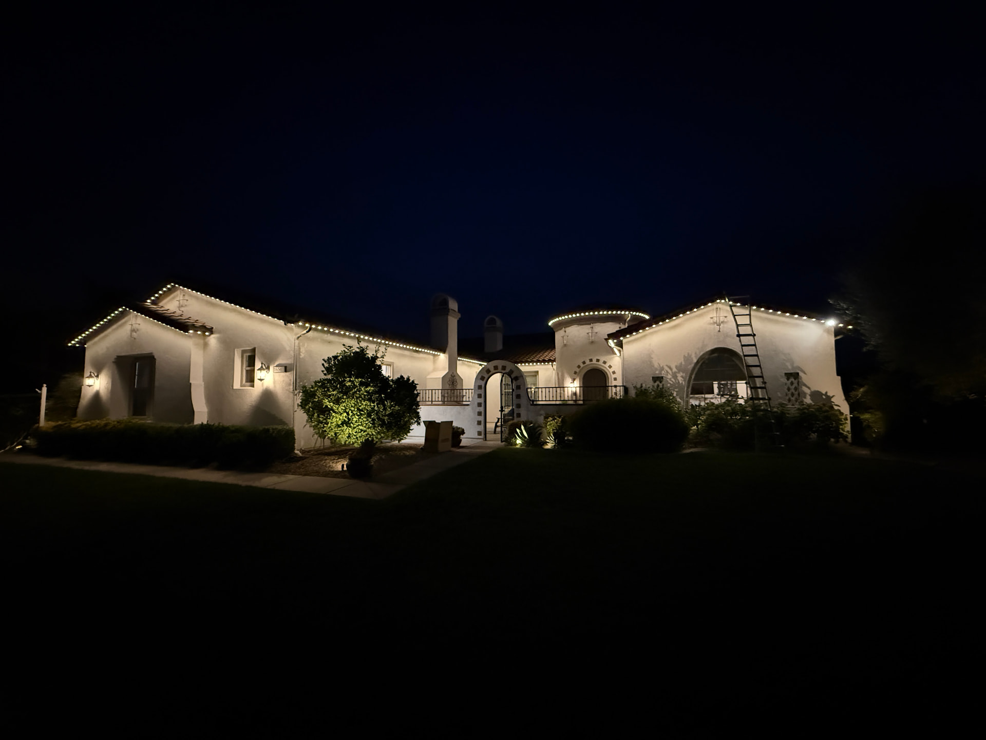 Warm white permanent lighting across a Spanish-style estate